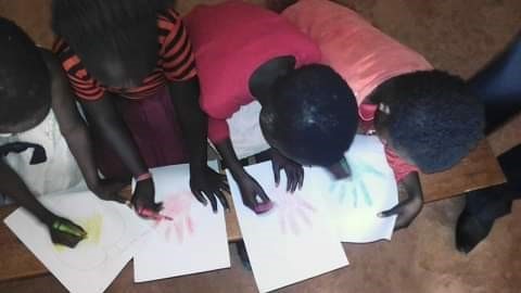 Four children work on coloring their handprints